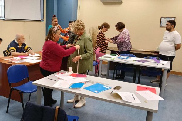 Los componentes de este taller utilizan a sus compañeras para aprender a tomar las medidas de las túnicas que van a confeccionar.